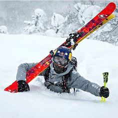 a person laying in the snow with skis on their back