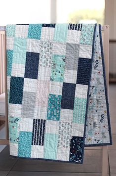 two quilts are hanging on the back of a crib, one is blue and white