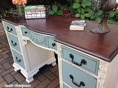 an old desk has been painted blue and white with flowers in the vase on top