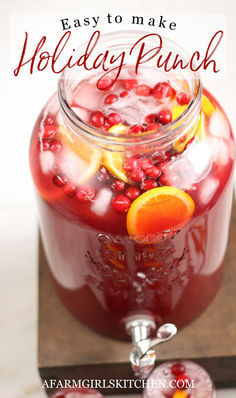 Red holiday punch in clear glass drink dispenser with cranberries, orange slices and ice cubes on wooden stand. Best Holiday Punch, Cranberry And Pineapple, Easy Holiday Drinks, Holiday Punch Recipe, Christmas Drinks Recipes, Alcoholic Punch Recipes, Non Alcoholic Punch, Party Punch Recipes, Alcoholic Punch