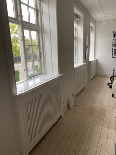 an empty room with wooden floors and white walls, windows on either side of the wall