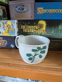 a white bowl sitting on top of a wooden shelf filled with books and other items