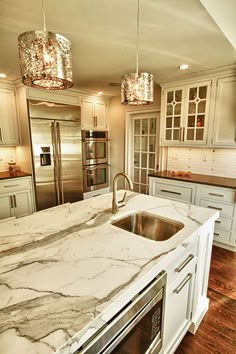 a large kitchen with marble counter tops and stainless steel appliances in the middle of it