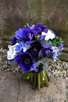 a bouquet of flowers sitting on top of a stone floor next to a rock wall