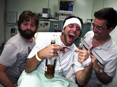 three men laughing and drinking beer in a hospital room