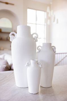 three white vases sitting on top of a table