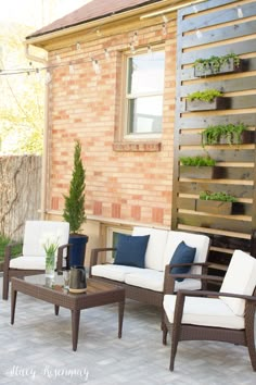 an outdoor living area with furniture and plants on the back deck, along with a brick wall