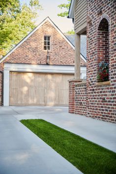 a brick house with grass in front of it and a garage door on the other side