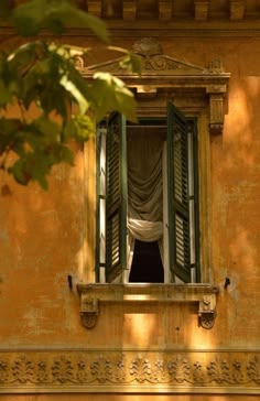 an open window with green shutters and curtains hanging from it's windowsill