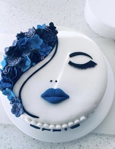 a white cake decorated with blue flowers and a woman's face