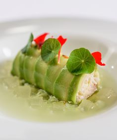 a white plate topped with cucumber slices covered in sauce and garnish