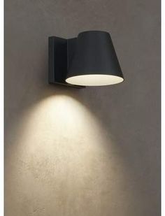 a wall light with a black shade on it's side against a white wall