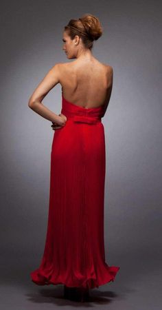 a woman in a red dress with her back turned to the camera, looking down