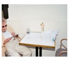 an older man sitting at a table with a glass of wine