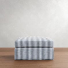 a blue and white striped footstool sitting on top of a wooden floor next to a wall