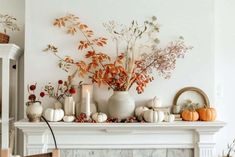 a fireplace mantel decorated with white pumpkins and greenery