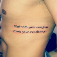 a person with a tattoo saying walk with your own feet, create your own history