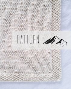 a white knitted blanket with a black bird on it's label that says pattern