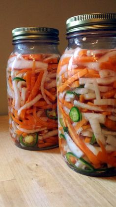 three mason jars filled with pickled carrots, onions and cucumber slices