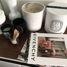 the contents of a givenchy bag are displayed on a table next to candles and other items