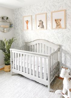 a white crib in a nursery with zebras and giraffes on the wall