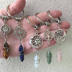 a person is holding several charms in their hand, including one with a compass and the other with an owl