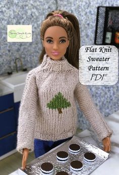 a doll is holding a tray with cupcakes on it and wearing a sweater