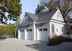 a two car garage sits in front of a white picket fence