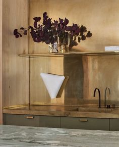 a vase with purple flowers sitting on top of a counter