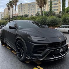 a black sports car is parked on the side of the road in front of some palm trees