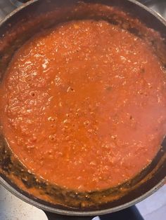 a pot filled with red sauce sitting on top of a stove