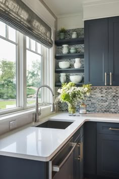 a kitchen with blue cabinets and white counter tops, along with a window over the sink