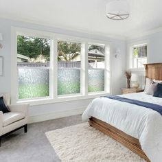 a bedroom with white walls and carpeted flooring, two windows on each side of the bed