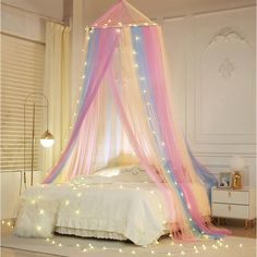 a canopy bed with pink, blue and yellow lights on the ceiling is decorated in pastel colors