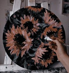 a person is painting a plate with flowers on the front and back sides in black, orange and white