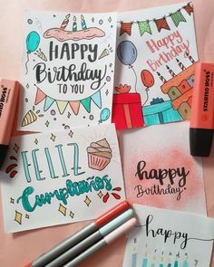 some birthday cards and markers on a pink surface with candles, balloons, and confetti