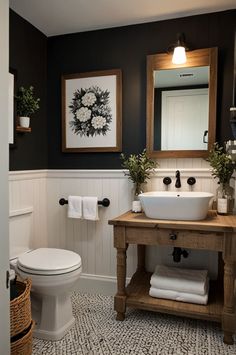 a white toilet sitting next to a sink in a bathroom under a framed painting on the wall