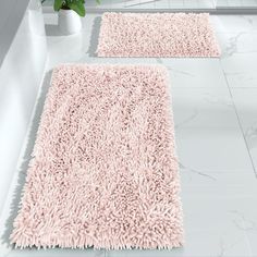 two pink rugs sitting next to each other on a white tile floor in a bathroom