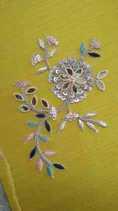 an embroidered yellow fabric with flowers and leaves on it