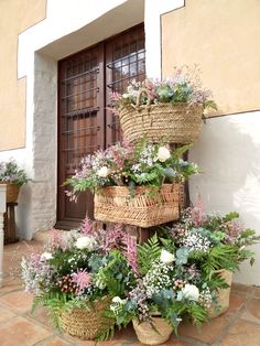 several baskets are stacked on top of each other in front of a building with flowers