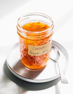 a glass jar filled with food sitting on top of a white plate next to a spoon