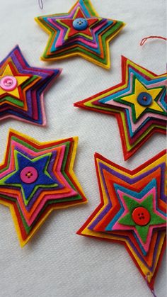 five brightly colored stars are hanging on a white tablecloth with string and buttons attached to them