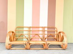 a bamboo bench sitting in front of a striped wall