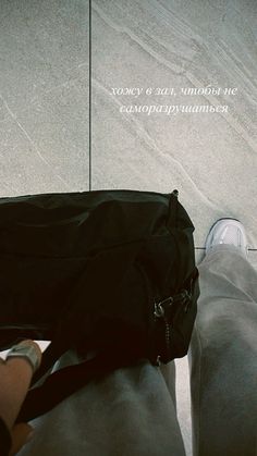 a person standing next to a black bag on top of a cement floor with words above it