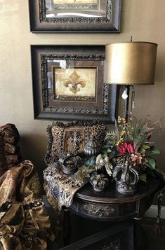 two framed pictures hang on the wall next to a table with vases and flowers