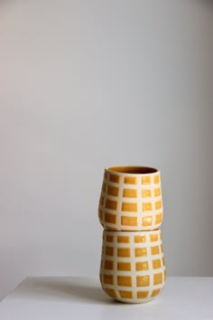 two yellow vases sitting on top of a white table