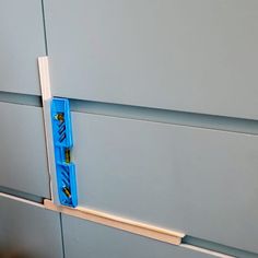 two pieces of blue tape are taped to the side of a gray wall with white trim