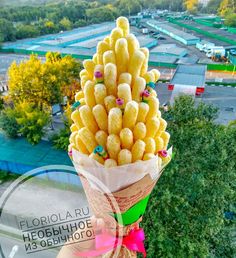 a person holding a bunch of food in front of a parking lot with trees and buildings