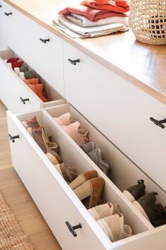 an open drawer with shoes in it on top of a wooden floor next to a table