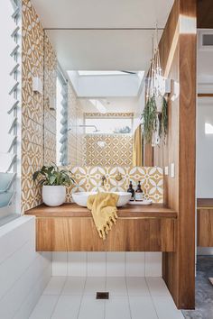 a bathroom with two sinks under a mirror and plants on the counter next to it